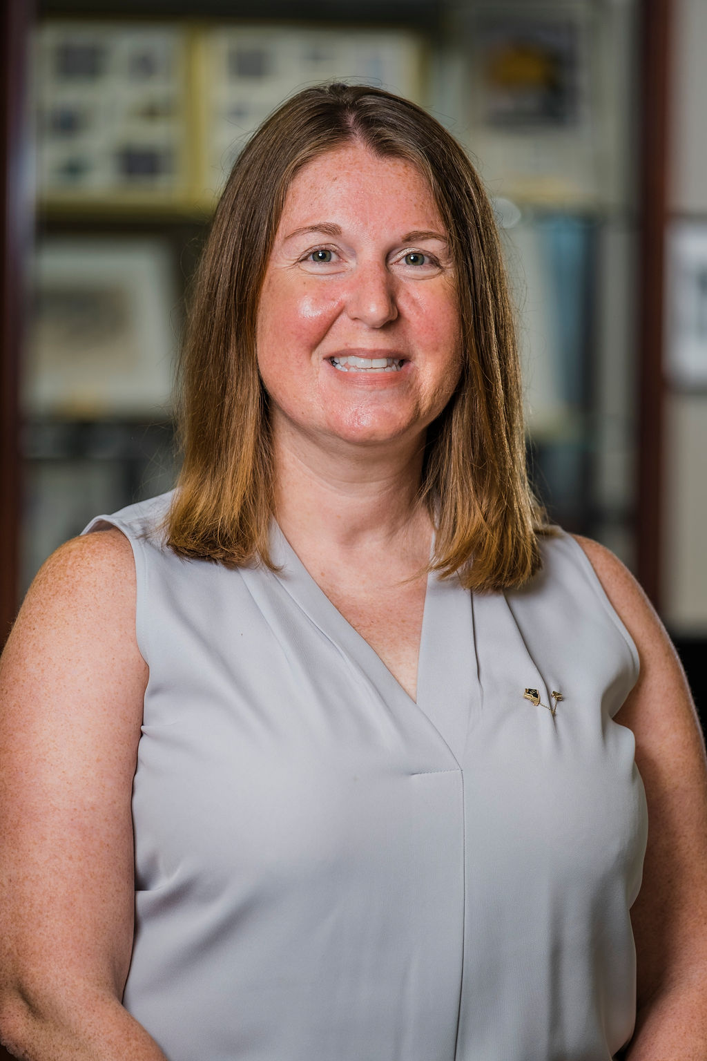 Headshot of Jenni Kemmery in front of book cases displaying Sorority archives.